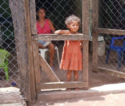 Young girl watches people pass her home